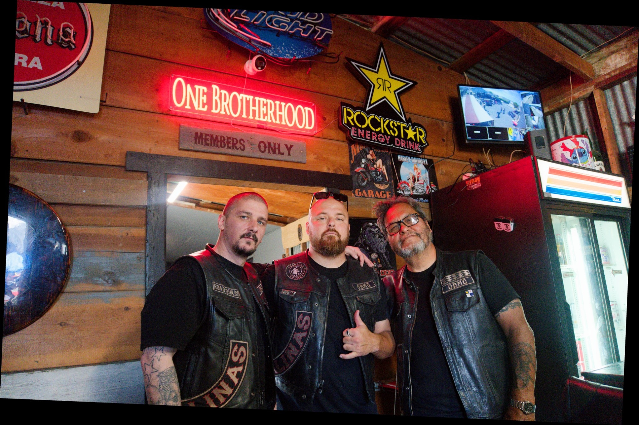 Three brothers under the One Brotherhood neon sign
